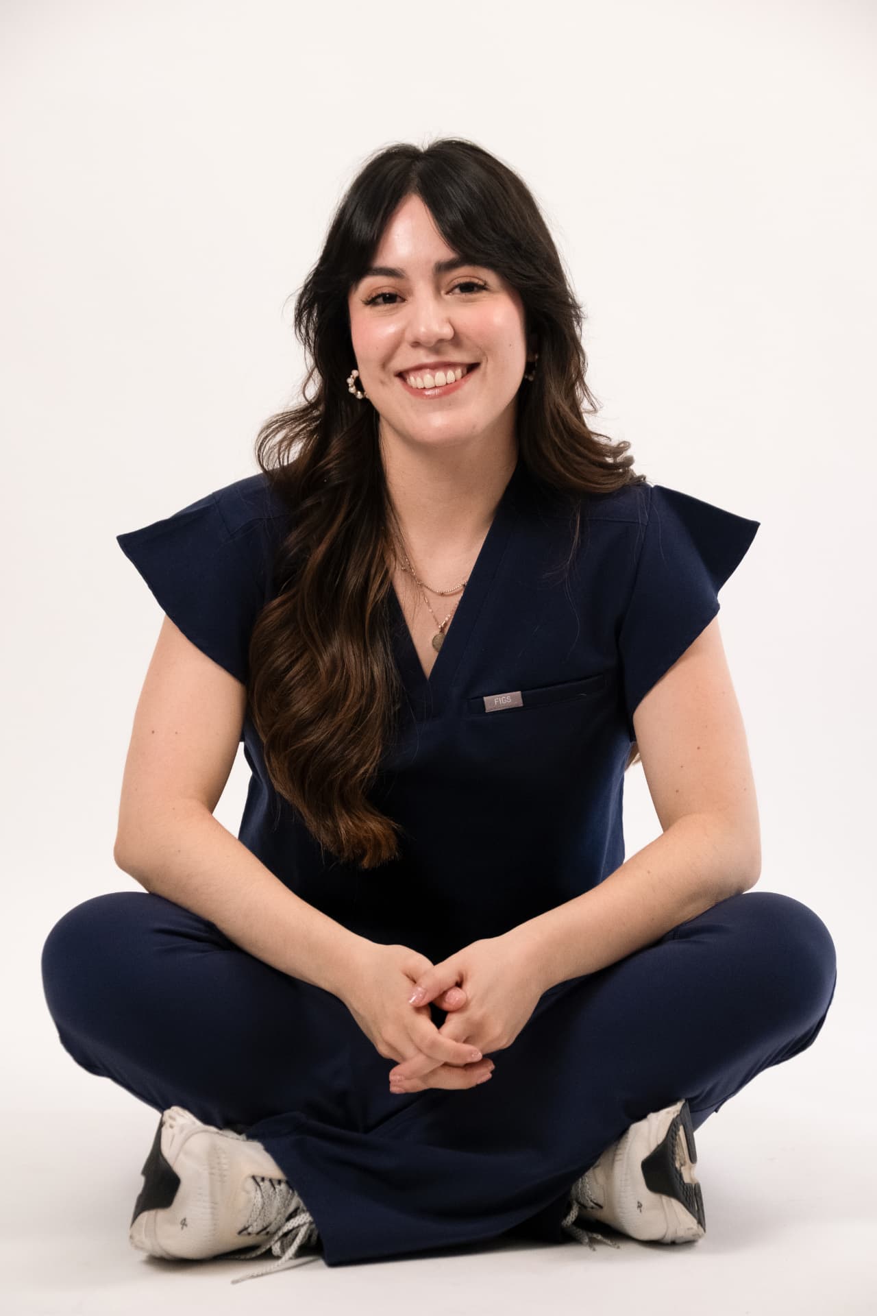 Dra. Laura Reyes sonriendo, sentada con uniforme médico azul marino